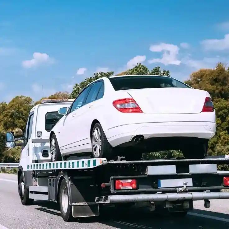 White car being safely loaded onto flatbed tow truck in Calgary.