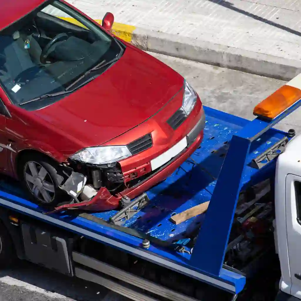 Damaged red car being loaded onto a tow truck for accident recovery service in Calgary by Tow Truck Calgary.