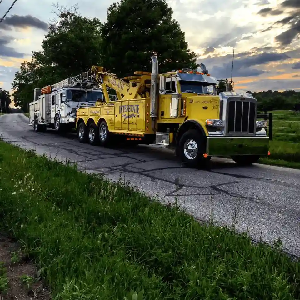 Heavy duty yellow wrecker tow truck towing large emergency vehicle on highway – Tow Truck Calgary