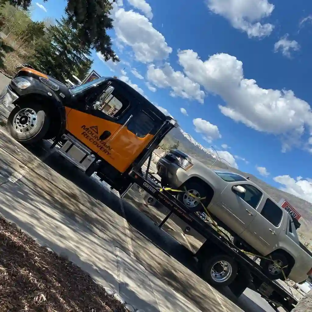 Heavy duty flatbed tow truck transporting silver pickup truck safely Tow Truck Calgary.