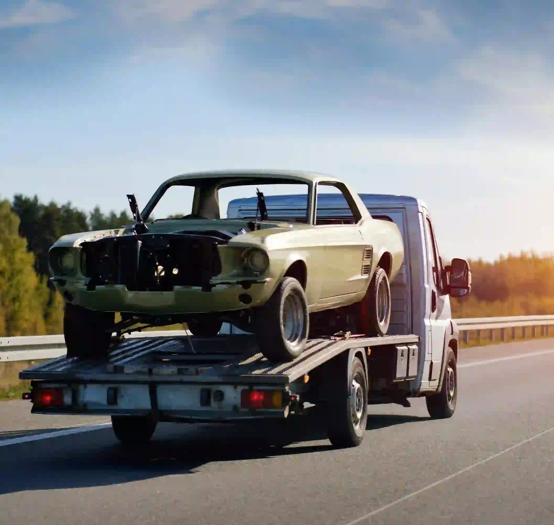 Flatbed tow truck transporting damaged car on highway Tow Truck Calgary.